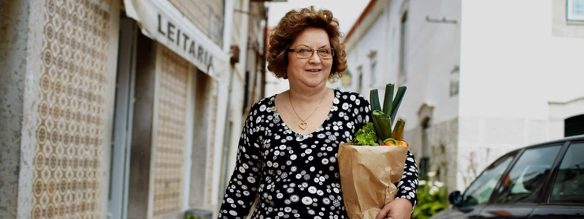 Market torbalarını taşıyarak sokakta yürüyen kadın.