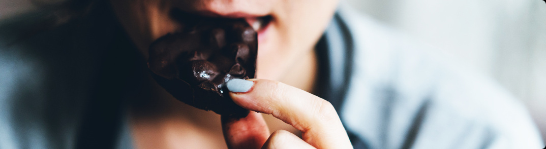 A cutout of a woman's face while eating chocolate.